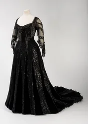 Robe du soir noire longue portée par la reine Alexandra, avec décor de perles et de paillettes et intégrant le ruban caractéristique en soie noire à lettres dorées portant le nom de la reine Alexandra, réalisée par Barolet de Knightsbridge, Londres