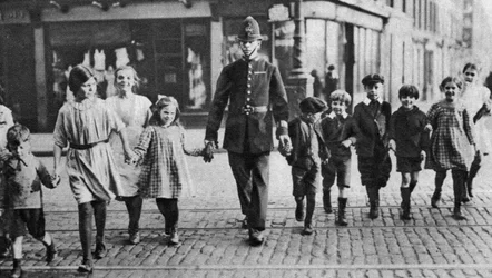 Policier aidant des écoliers à traverser la route, East End, Londres, 1926-1927