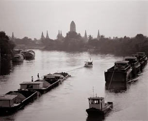 Péniches descendant la rivière Chao Phraya avec vue sur Wat Chaiwatthanaram