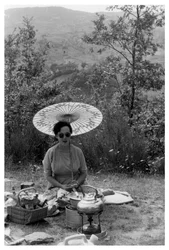 Femme sous une ombrelle faisant un pique-nique, vers 1950-1969