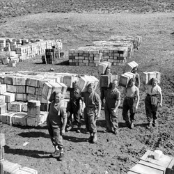 Un dépôt de rations composées et des hommes transportant plus de fournitures, mars 1943