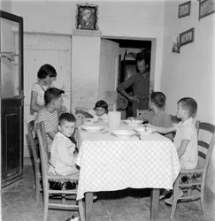 Grande famille réunie à table dans la salle à manger de la maison de campagne. Années 1960
