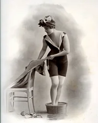 Jeune femme en maillot de bain (de la Belle Époque) prenant un bain de pieds, vers 1900 (photo n/b)