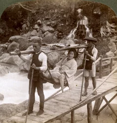 Femme japonaise dans une chaise de montagne yamakago traversant la rivière torrentielle Daiya près de Nikko, Japon