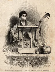 Une chanteuse de légendes nationales, jouant du shamisen pour accompagner son chant, assise derrière son pupitre. Gravure pour illustrer le voyage au Japon, en 1863-1864, d
