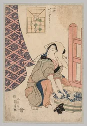 Femme assise lavant des vêtements dans une cuve en bois
