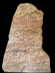Une stèle avec des inscriptions runiques représentant un cavalier viking avec un chien
