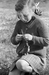 Petite fille créant un collier de marguerites