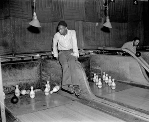 Homme afro-américain assistant aux quilles dans une salle de bowling, pour réinitialiser manuellement les quilles