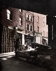 Paniers de fruits empilés contre des maisons au Borough Market, Londres, 1926-1927