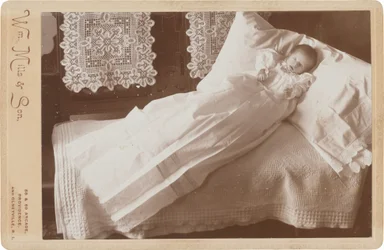 Bébé post-mortem sur un lit, années 1880-1890 (photo)