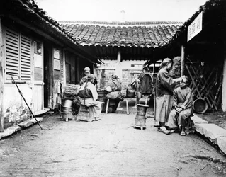 Barbiers itinérants dans une maison de campagne, Chine, c.1875