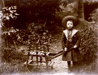 Fille avec une charrette dans un jardin, début du 20ème siècle